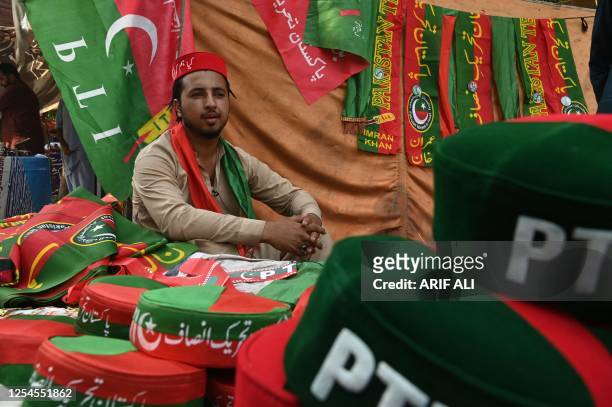 Mohsin Khan, an activist of Pakistan Tehreek-e-Insaf party and supporter of former prime minister Imran Khan, sells party flags and caps near Khan's...