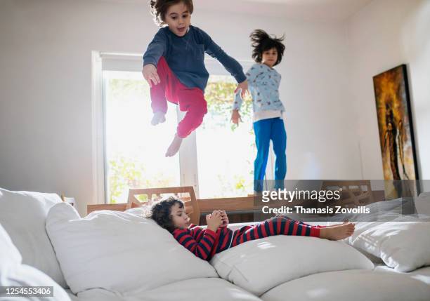small kids having fun indoor while their brother using a digital tablet - gruppe springen ipad stock-fotos und bilder