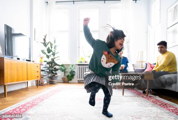 parents looking at daughter dancing in living room - indian living room stock pictures, royalty-free photos & images