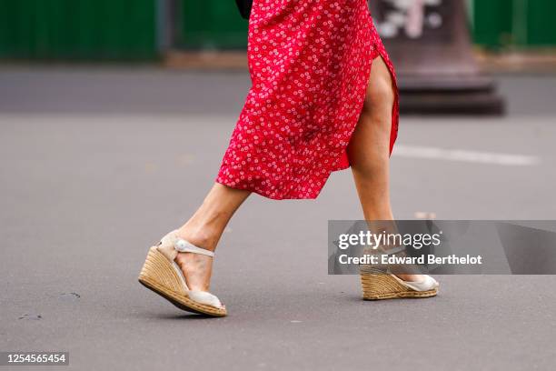 Passerby wears a red floral print dress, wedge platform shoes with wooden heels, on July 04, 2020 in Paris, France.