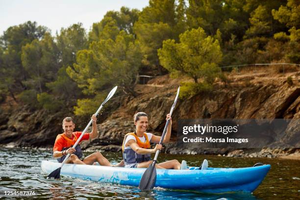 sonriente pareja kayak en el río en vacaciones de verano post covid-19 - piragüismo fotografías e imágenes de stock