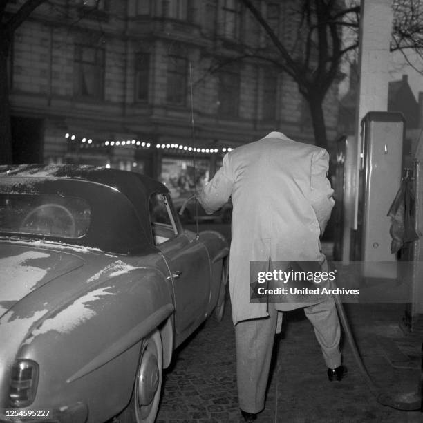 Der kopflose Jazzpianist und Komponist Fritz Schulz - Reichel mit seinem Mercedes Benz 190 SL Cabrio an der Zapfsäule einer Tankstelle, Hamburg 1955.
