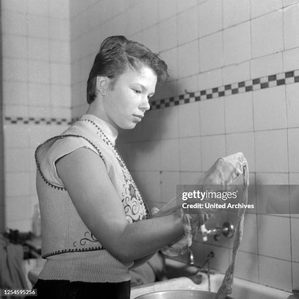 Eine junge Frau bei der Handwäsche einer Strumpfhose, Hamburg 1955.