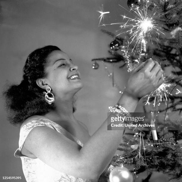 Die karibische Blues-, Pop- und Schlagersängerin Mona Baptiste erfreut sich am Weihnachtsbaum, Hamburg 1955, Caribbean singer and actress Mona...