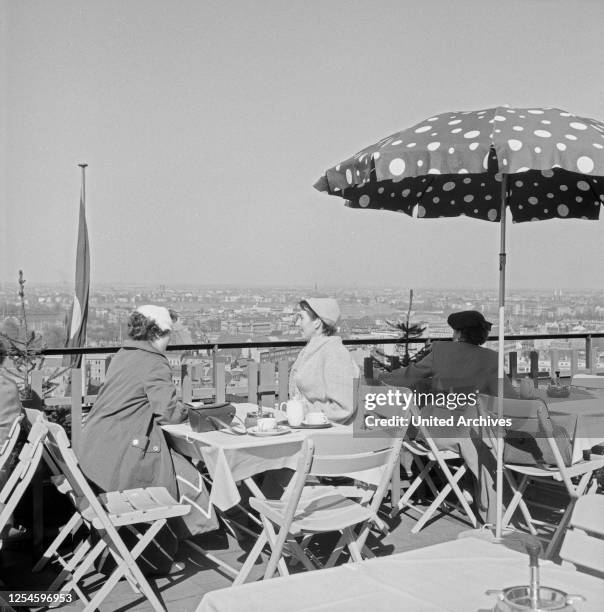 Menschen sitzen 1956 in einem Dachgarten Restaurant und genießen bei Kaffee den Ausblick auf die Stadt Hamburg.