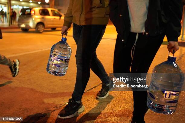 Pedestrians carry jugs of bottled water in Montevideo, Uruguay, on Friday, May 12, 2023. Uruguay's government is now subsidizing bottled water in the...