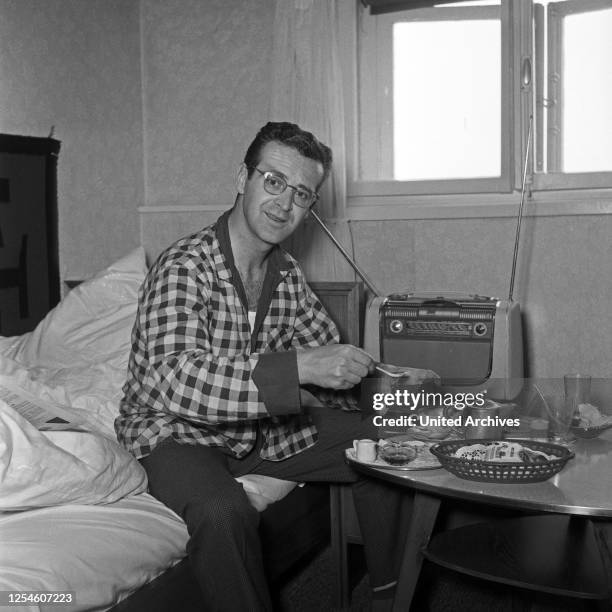 Der Schweizer Musiker, Sänger und Orchesterleiter Hazy Osterwald beim Frühstück im Bett, Deutschland 1950er Jahre.