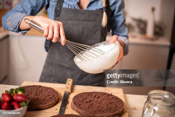 donna che cuoce a casa, preparazione della torta gocciolante: preparare la panna montata - frusta foto e immagini stock