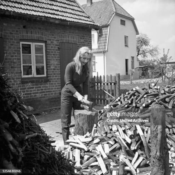 Die deutsche Schauspielerin Karin Stoltenfeldt beim Holzhacken, Deutschland 1950er Jahre.