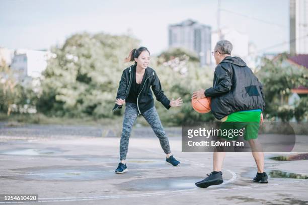 un homme chinois asiatique senior pratiquant le jeu de boule de panier dans le court de boule de panier le matin avec sa fille - father son challenge round two photos et images de collection