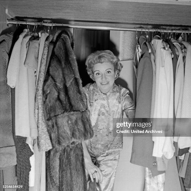 Die Fernsehansagerin Angelika Feldmann beim Blick in den Kleiderschrank, Deutschland 1950er Jahre.