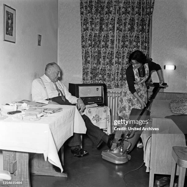 Ein Raumpflegerin staubsaugt im Zimmer eines Bewohners der Stiftung Seefahrtsdank in Hamburg ab, Deutschland 1960er Jahre.