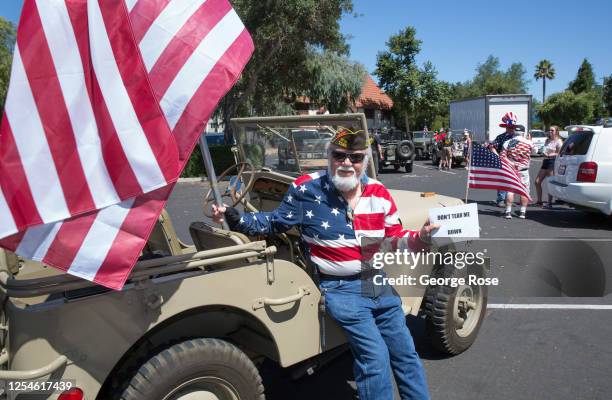 Veteran poses with an American flag before getting in his World War II Jeep for an impromtu parade around town on July 4 in Solvang, California....