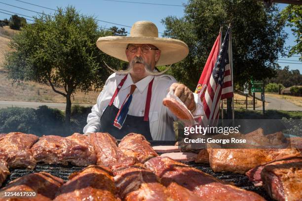 "Barbecue Billy" cooks Santa Maria-style tri-tip and ribs outside in the 90-degree heat on July 4 in Solvang, California. Despite the on-going...