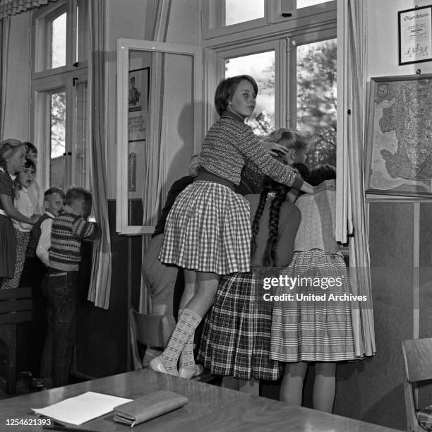 Neugierig hängen die Kinder am Fenster vom Schulgebäude in Lüdersbüttel im Kreis Norderdithmarschen in Schleswig Holstein am Tag als ihr eigener...