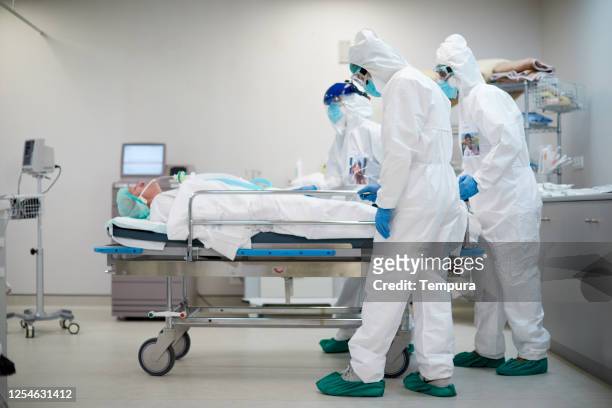 tired and sad healthcare workers pushing a hospital gurney - covid 19 stock pictures, royalty-free photos & images