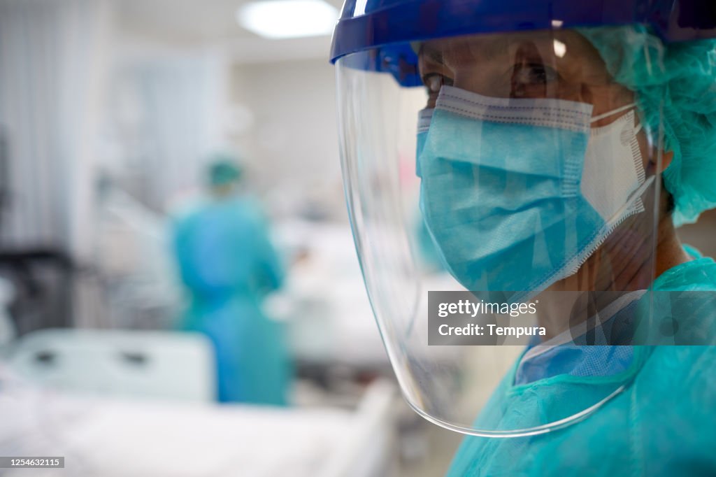 Vista de cerca de un docotr usando una máscara quirúrgica y un protector facial.