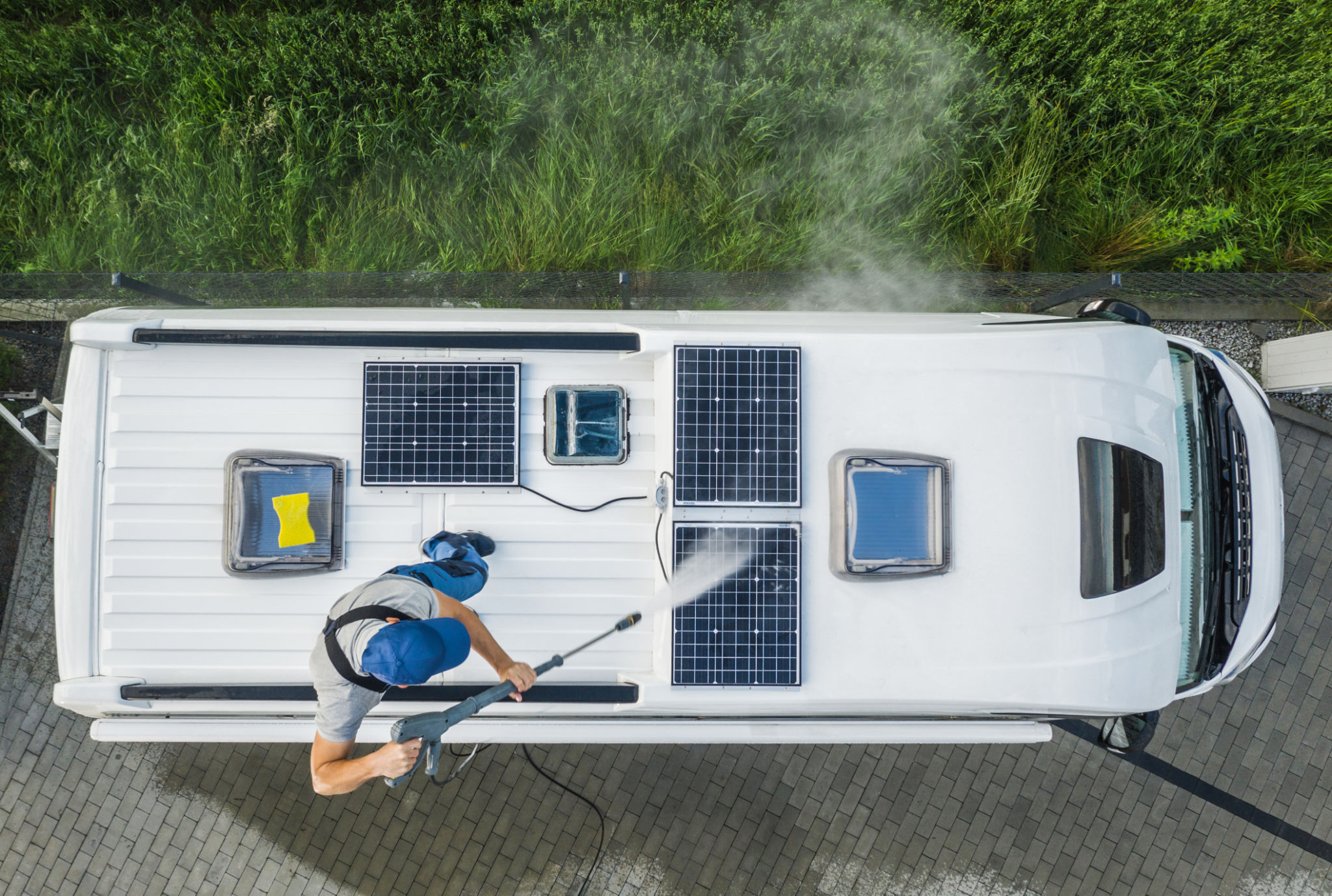 Men Pressure Washing RV Camper Van Roof Equipped with Solar Panels Men Pressure Washing RV Camper Van Roof Equipped with Solar Panels