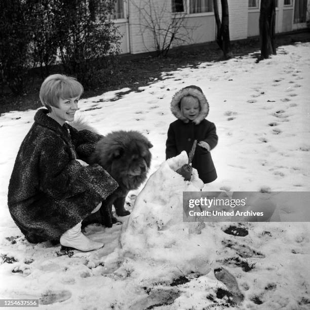 Die deutsche Schauspielerin Ingrid van Bergen mit ihrer Tochter Carolin und Hund im Schnee, Deutschland 1960er Jahre.