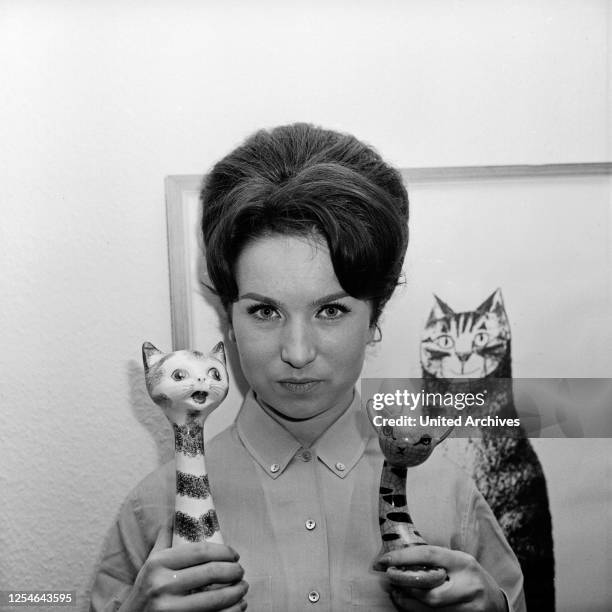 Die NDR Nachrichtensprecherin und Moderatorin Brigitte Gerloff mit zwei Deko-Katzen, Deutschland 1960er Jahre.