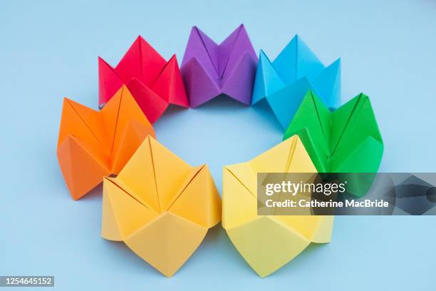 paper fortune tellers arranged by colour on a blue background - catherine macbride stock pictures, royalty-free photos & images