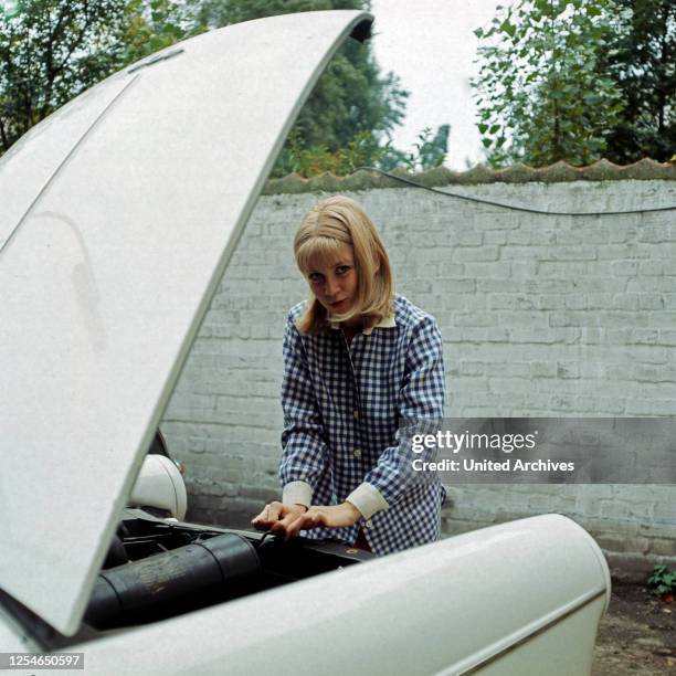 Die dänische Sängerin Gitte Haenning bastelt an einem Peugeot, Deutschland 1970er Jahre.