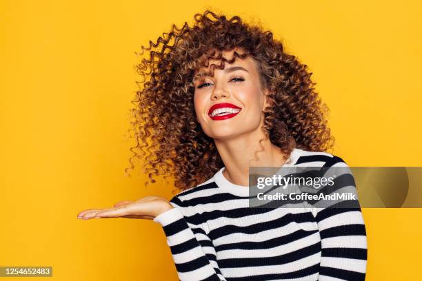 belle femme avec les cheveux bouclés démontre votre produit - pop photos et images de collection