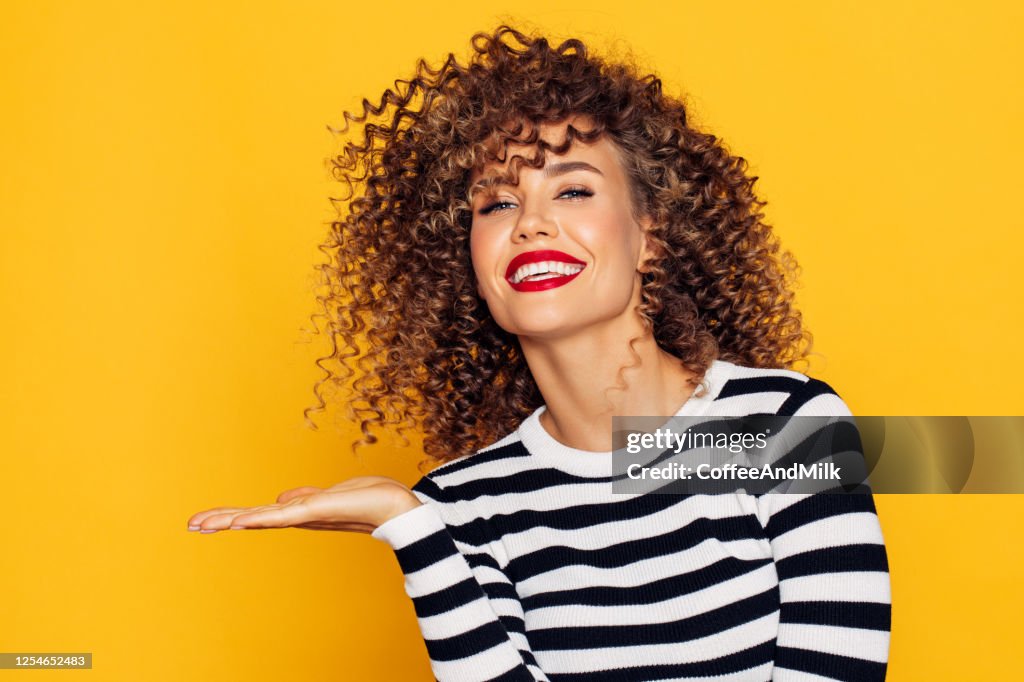 Mulher bonita com cabelo encaracolado demonstra seu produto