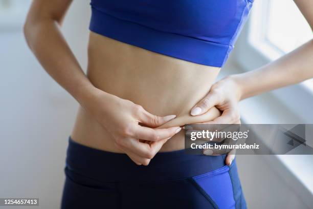 mujer tocando su vientre gordo - fat fotografías e imágenes de stock