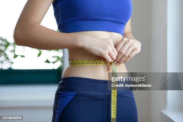 onherkenbare jonge vrouw die haar taille meet - weight loss stockfoto's en -beelden