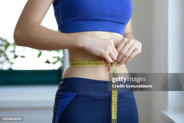 無法辨認的年輕女子測量她的腰部 - weight loss 個照片及圖片檔