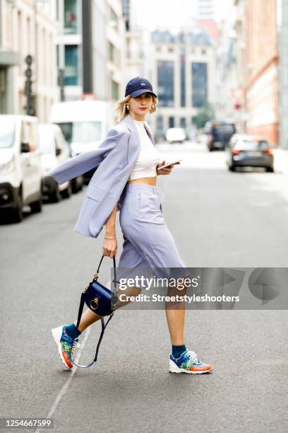 Influencer Kimyana Hachmann wearing a blue short suit by Arket, a dark blue cap by Lacoste, a drak blue bag by Chloe and multicolored sneakers by...