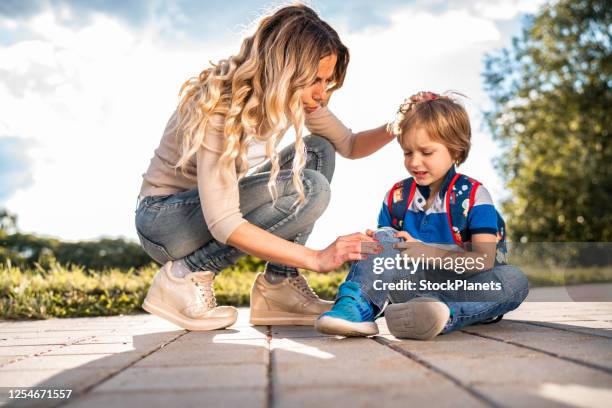 moeder helpt haar zoon met een gewonde knie - knee length stockfoto's en -beelden