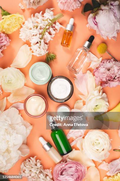 assorted flowers around natural cosmetics - cosmetic bottle stockfoto's en -beelden