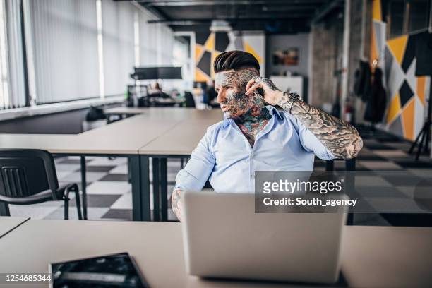 uomo d'affari con tutto il corpo coperto di tatuaggi in ufficio - body language at work foto e immagini stock