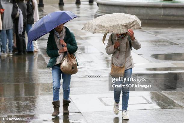 Members of public shelter under umbrellas during wet weather in central London. The Met Office forecast temperatures in London to reach 20 degrees...