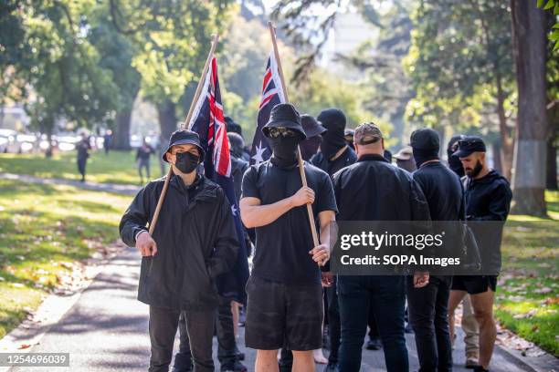 Neo-Nazis stand holding Australian flags during the demonstration. A day of political tensions and clashes unfolded in Melbourne as a far-right...