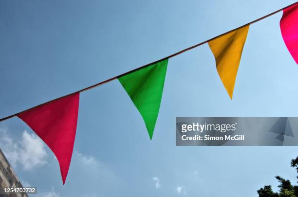 plastic triangular plastic bunting hanging across a street - mexican bunting stock pictures, royalty-free photos & images