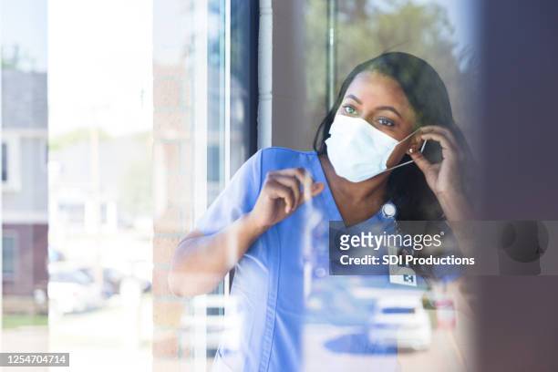 krankenschwester setzt auf schützende gesichtsmaske - essenzielle berufe und dienstleistungen stock-fotos und bilder