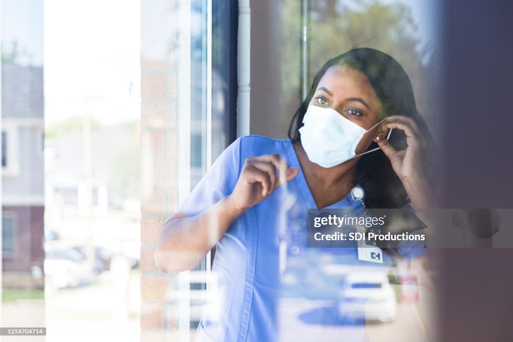 De verpleegster zet beschermend gezichtsmasker op