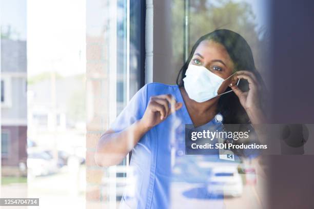 nurse puts on protective face mask - essential services stock pictures, royalty-free photos & images