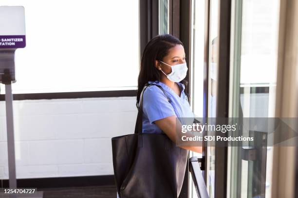 nurse is ready for her shift as she walks into hospital - entering hospital stock pictures, royalty-free photos & images