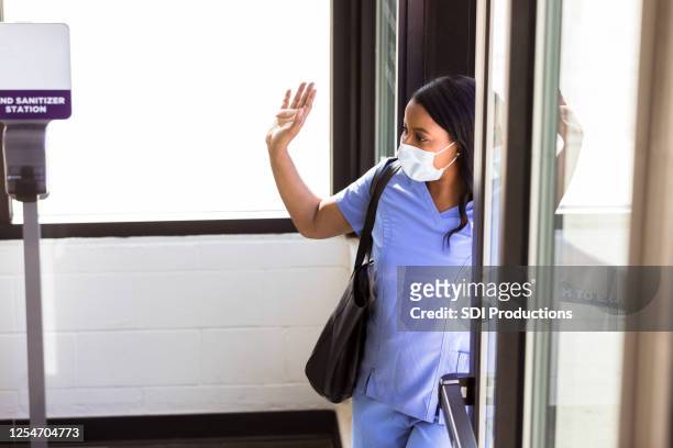 nurse with mask waves goodbye to co-workers - nurse leaving stock pictures, royalty-free photos & images