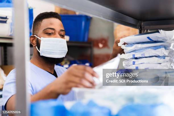 mannelijke arts selecteert benodigdheden voor het zien van patiënten tijdens covid-19 - face mask protective workwear stockfoto's en -beelden