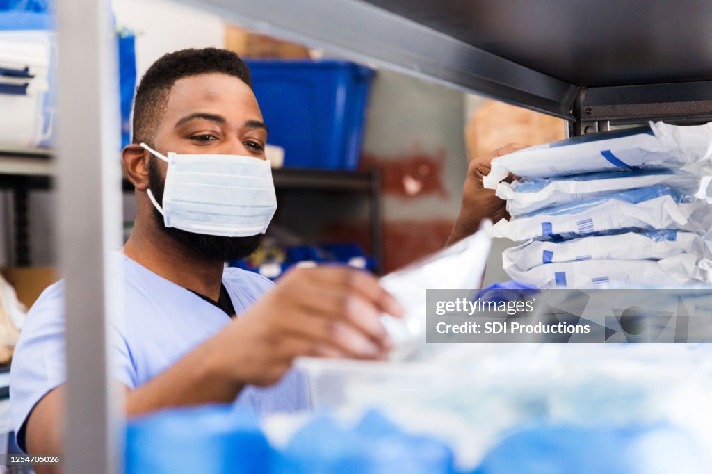 Médico do sexo masculino seleciona suprimentos antes de atender pacientes durante o COVID-19