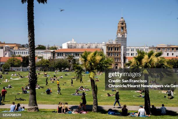 People enjoy the sunny afternoon in the social distancing circles at Dolores Park on Saturday, July 4 in San Francisco, Calif. Health officials...