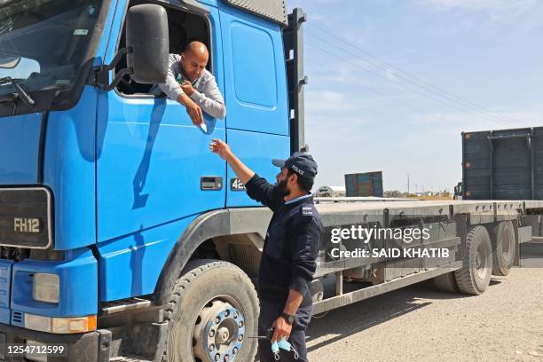 Palestinian officer checks the documents of a truck driver at at the Kerem Shalom border crossing in Rafah on May 14, 2023 as Israel gradually...