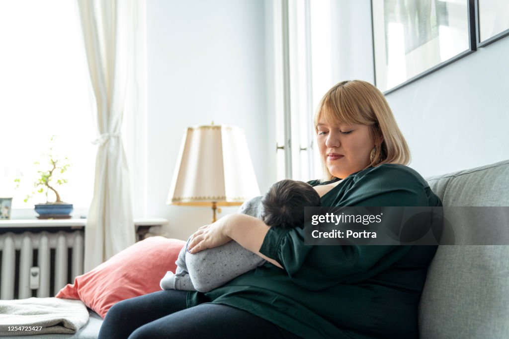 Mother breastfeeding son at home