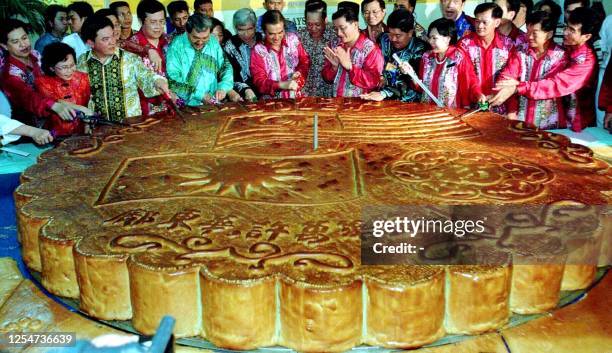 Malaysian ministers led by Deputy Prime Minister Abdullah Ahmad Badawi and members of the public cuts a giant mooncake during a celebration to mark...