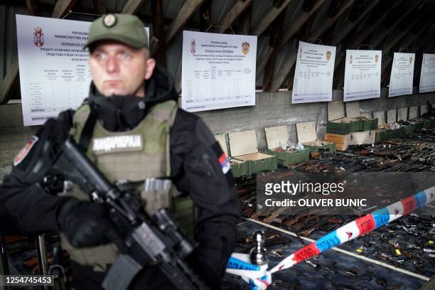 Serbian police officer stands in front of weapons collected in the latest government disarmament program following recent mass shootings in the...